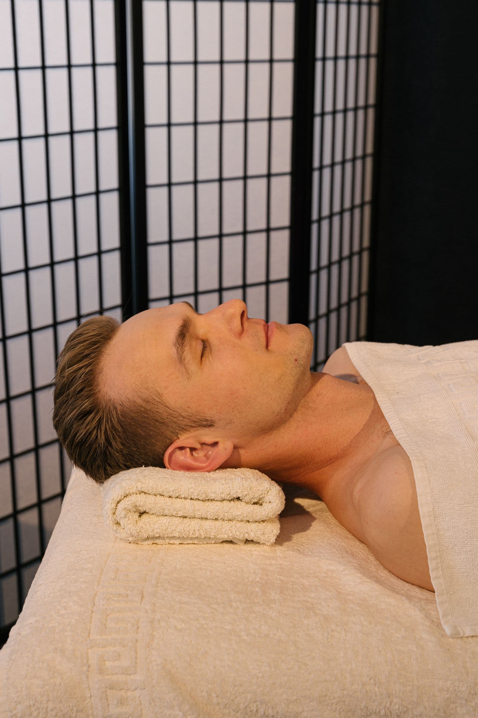 Relaxed male guest resting on a massage table in a private spa setting